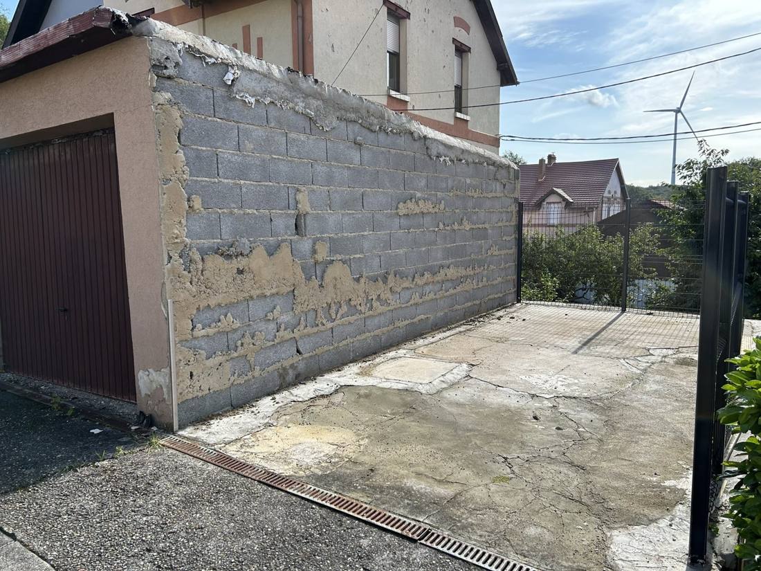 Cour en béton fissuré et mur en parpaings avant travaux